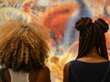 two women looking at painting with braids and afro hair